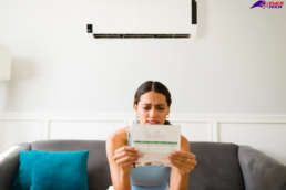Tips to Lower Your AC Bill - young woman looking over her high Air Conditioning bills