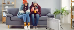 No Heat at Home This Could Be the Reason Why - Man and woman freezing cold sitting near space heater, because their HVAC heating broke down Philadelphia