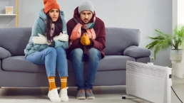 No Heat at Home This Could Be the Reason Why - Man and woman freezing cold sitting near space heater, because their HVAC heating broke down Philadelphia
