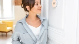 Thermostat Repair and Installation - EMCO Tech - Young Woman Looking at Smart Thermostat