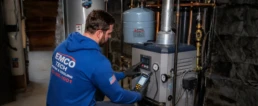 HVAC technician checking boiler controls and system pressure during seasonal service