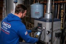 HVAC technician checking boiler controls and system pressure during seasonal service